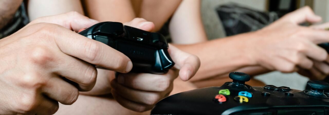 Close-up of adults playing video games with joysticks. Intense multiplayer gaming session.
